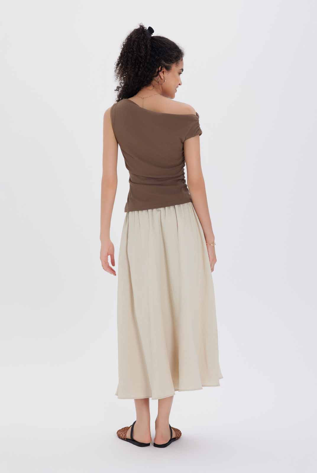 A brown one-shoulder top and beige skirt
